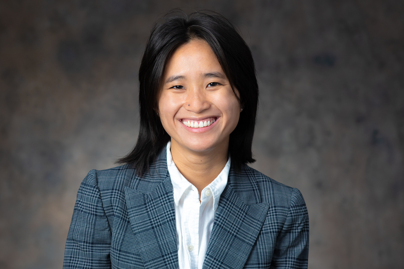 Portrait of a smiling young woman in a plaid blazer, MIL Team member