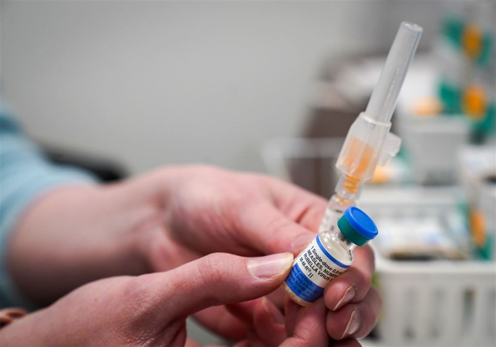Hands hold vaccine vial and syringe