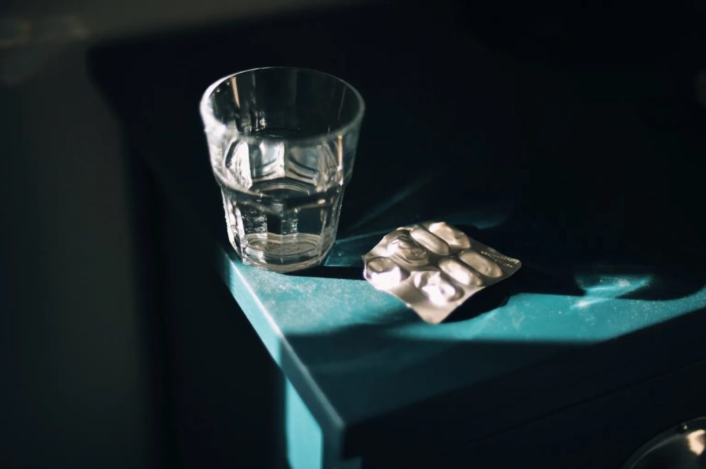 Pill blister pack and glass of water on a table, illustrating RX Roulette.